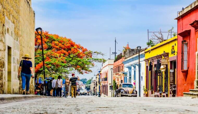 在墨西哥瓦哈卡的一个阳光灿烂的日子里，一条色彩缤纷的街道上挤满了行人